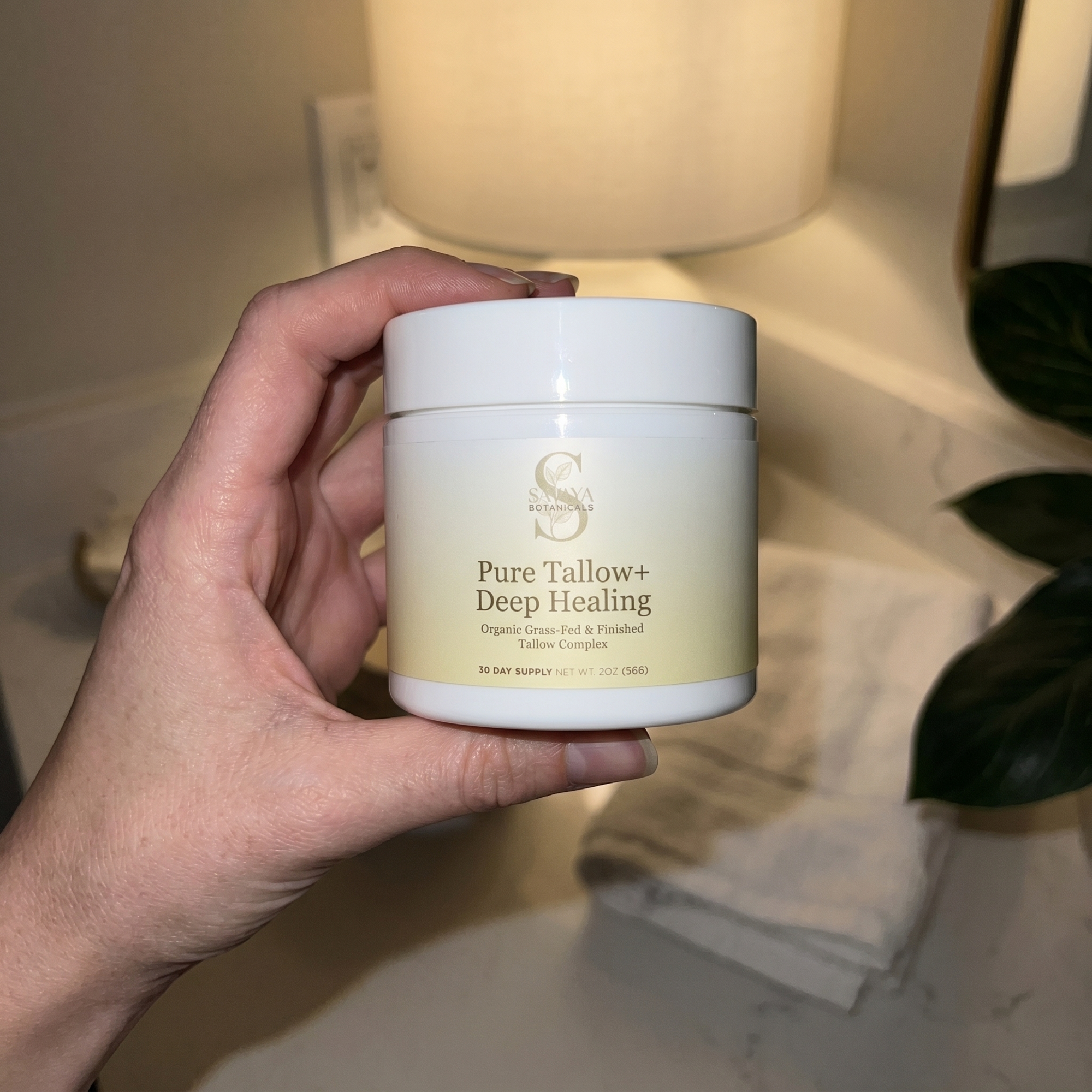 Hand holding Pure Tallow+ Deep Healing jar bathroom vanity night